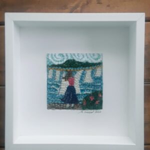 punch needle art of clothesline with pink flowers by the ocean